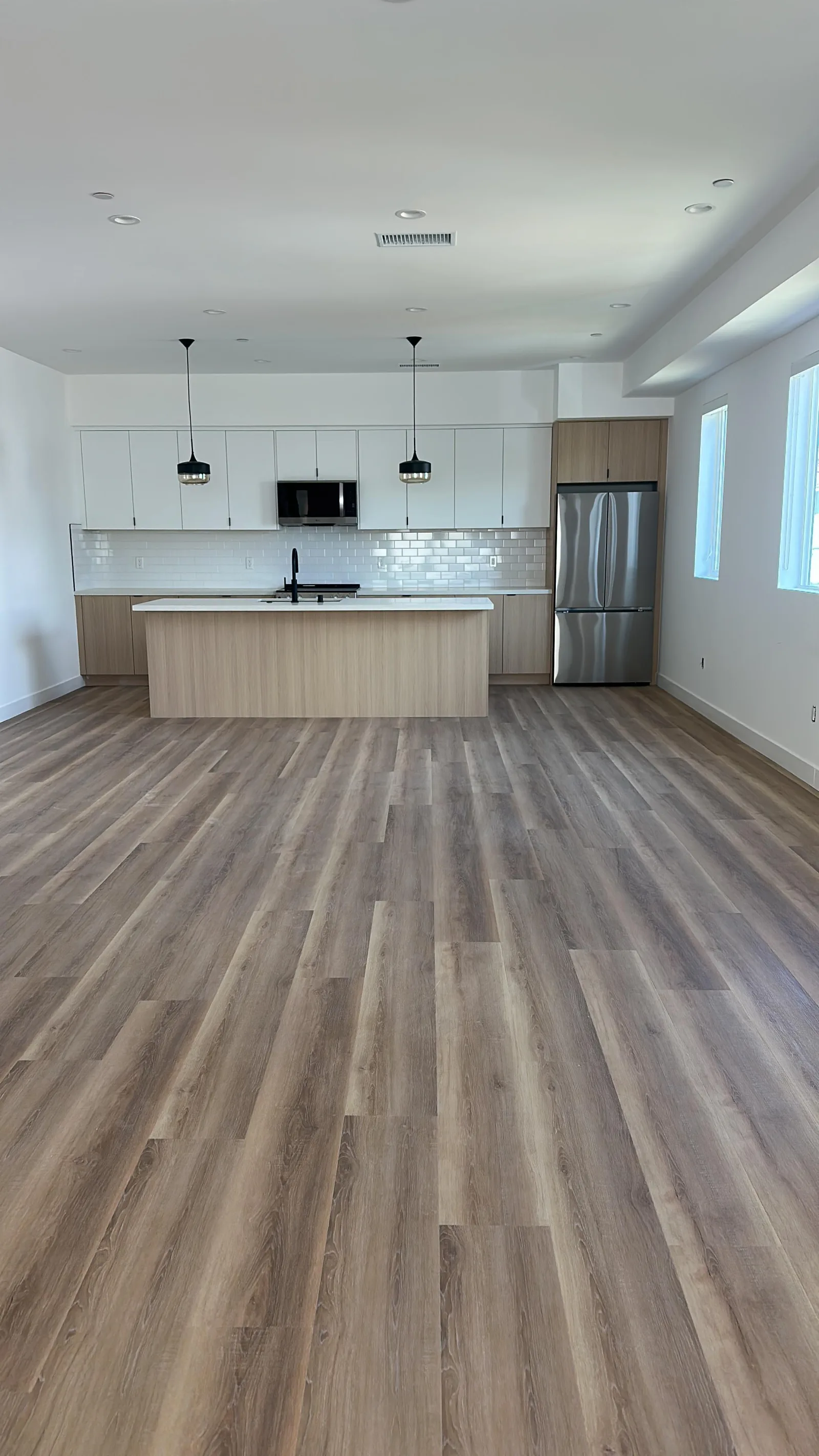Open-concept white kitchen with luxury vinyl plank flooring